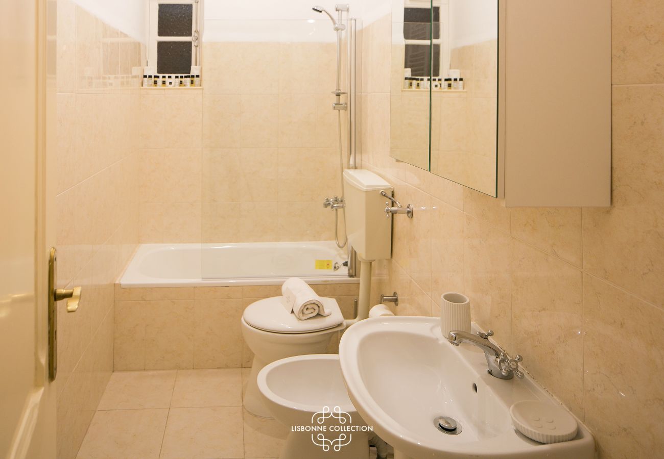 salle de bain beige avec grande baignoire, bidet et vasque